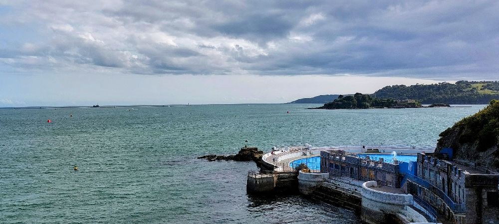 An uninterrupted view of the Eddystone Lighthouse, jus barely visible on the horizon, in the middle of the picture.